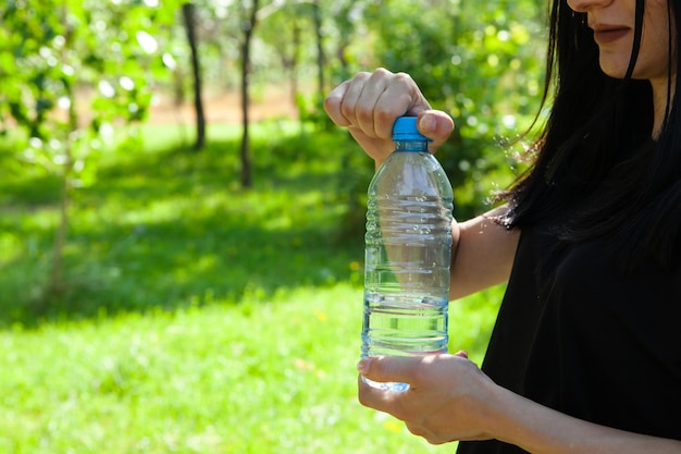 Vrouwenhand met een fles water in het park