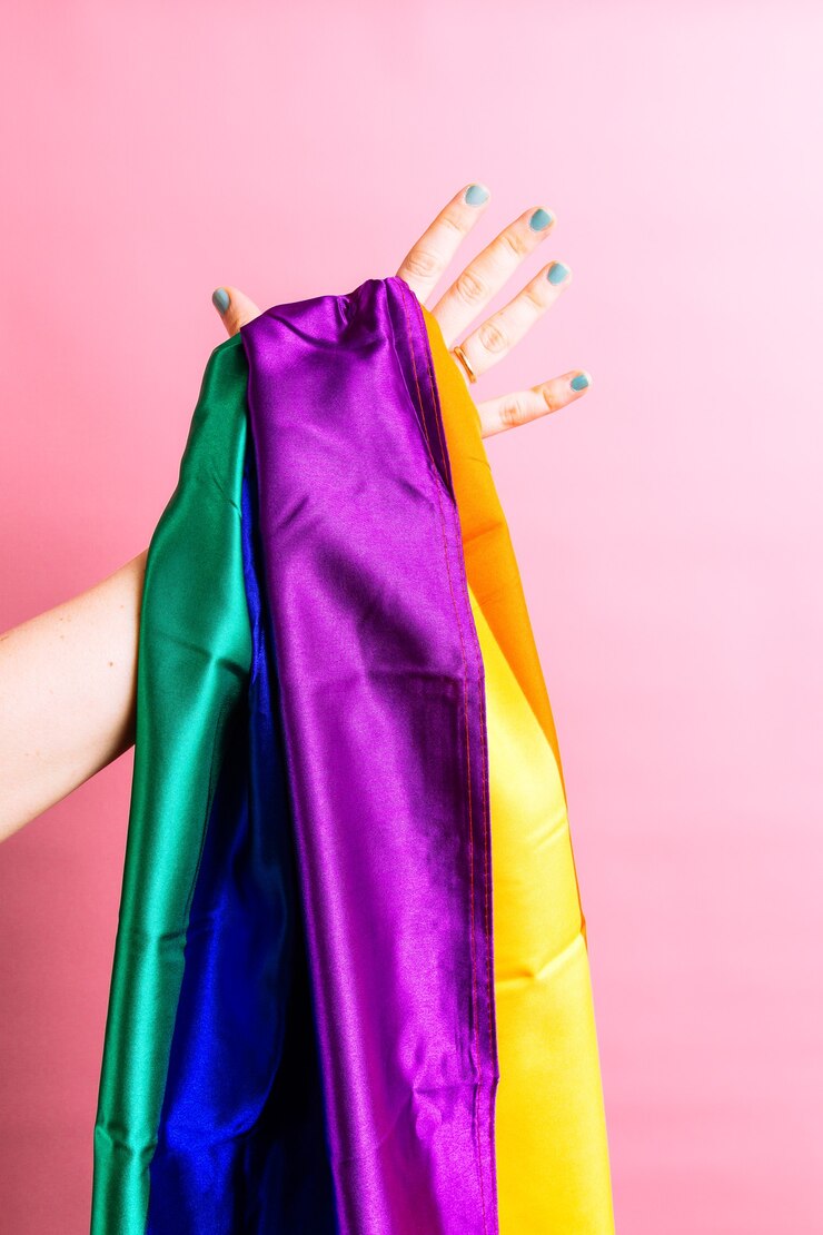 Vrouwenhand met groen geschilderde spijkers die een lgbtq-vlag op kleurrijke vlakke achtergrond houden. lesbisch concept