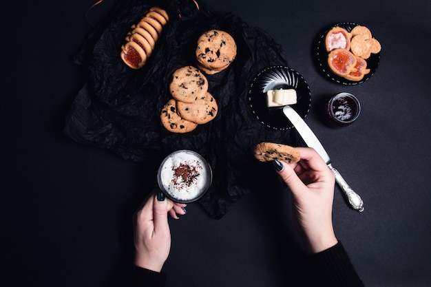 Vrouwenhand met kop koffie of cappuccino en chocoladekoekjes, koekjes