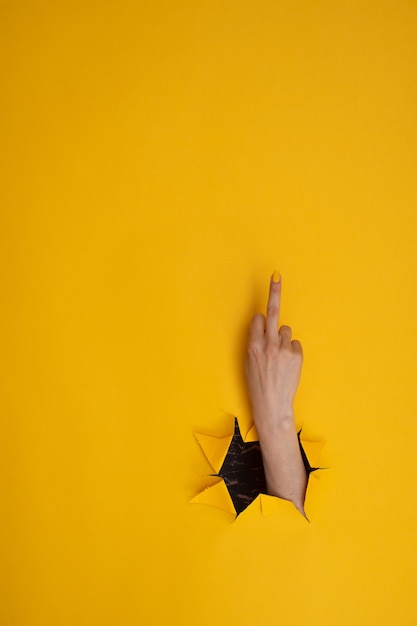 Vrouwenhand met middelvinger, neuken op een gele achtergrond. Handgebaren