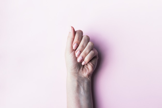 Vrouwenhand met roze nude nagels met kleine zwarte stippen