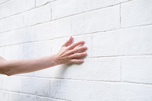 Vrouwenhand op de achtergrond van een witte bakstenen muur