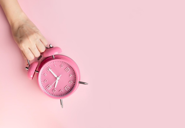 Vrouwenhand pakt roze wekker time management