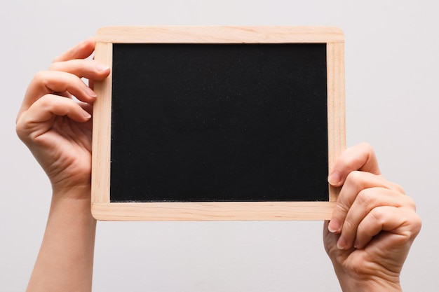 Vrouwenhand toont krijtbord Plaats voor het schrijven van tekst op een zwart bord Handen die een leeg zwart bord op wit houden
