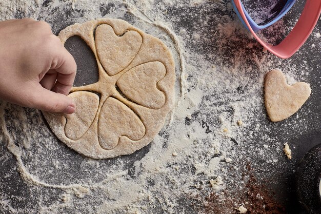 Vrouwenhanden bereiden koekjes in de vorm van harten voor Valentijnsdag