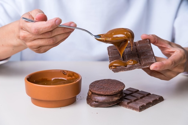 Vrouwenhanden die dulce de leche op chocolade zetten die niet geschikt is voor diabeticixA