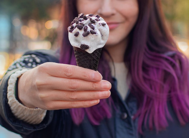 Vrouwenhanden die een chocolade oreo-ijskegel in de openlucht houden lente