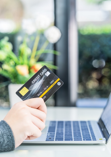 Vrouwenhanden die een creditcard voor online het winkelen houden