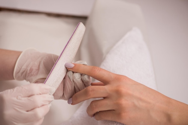 Vrouwenhanden die een manicure in schoonheidssalon ontvangen. Nagel vijlen. Close-up, selectieve aandacht.