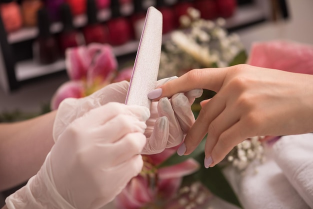 Vrouwenhanden die een manicure in schoonheidssalon ontvangen. Nagel vijlen. Close-up, selectieve aandacht.