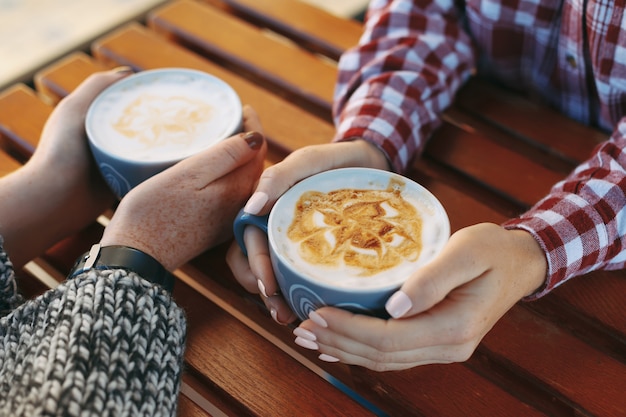 Vrouwenhanden die met sproeten koppen van koffie houden