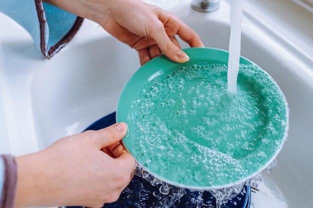 Vrouwenhanden die plaat in gootsteen wassen