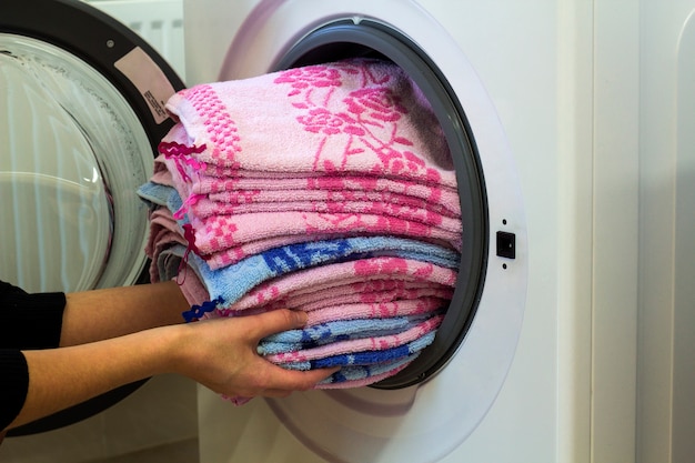 Vrouwenhanden die wasserij thuis zetten in wasmachine