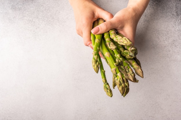 Vrouwenhanden houden een bosje verse groene asperges vast