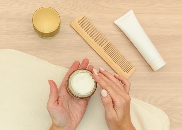 Vrouwenhanden houden een pot cosmetische crème vast Handen liggen op een witte handdoek