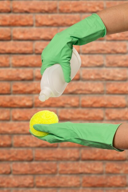 Vrouwenhanden in beschermende handschoenen met fles afwasmiddel
