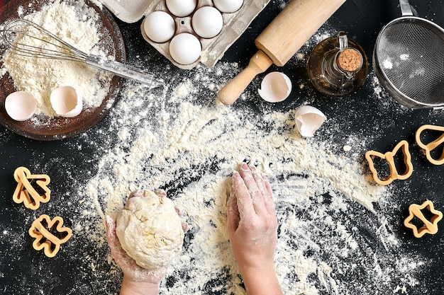 Vrouwenhanden kneden deeg op tafel met bloemeieren en ingrediënten Bovenaanzicht