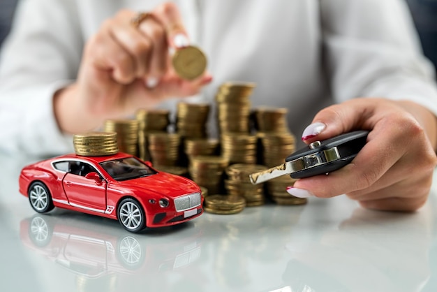 Vrouwenhanden knuffelen een automodel op een stapel dollars op een glazen tafel