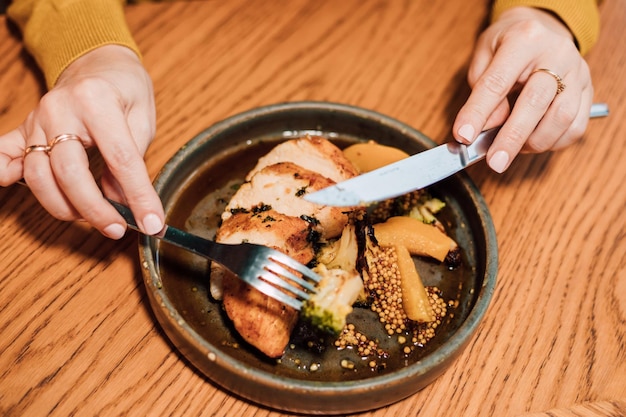Vrouwenhanden met een vork en mes over een bord eten