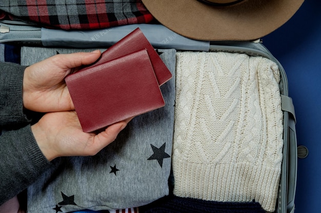 Foto vrouwenhanden met paspoorten op de achtergrond open koffer ingepakt voor reizen wintervakanties en vakanties bovenaanzicht