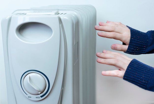 Vrouwenhanden reiken naar de radiator om warm te blijven