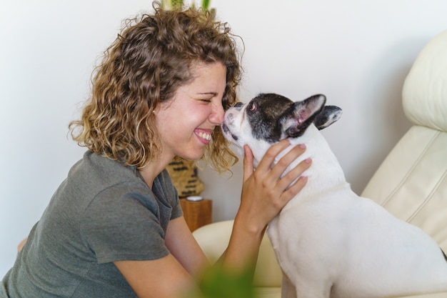 Foto vrouwenhondenliefhebber met buldog thuis. horizontale weergave van een vrouw die zoent en speelt met de hond binnenshuis