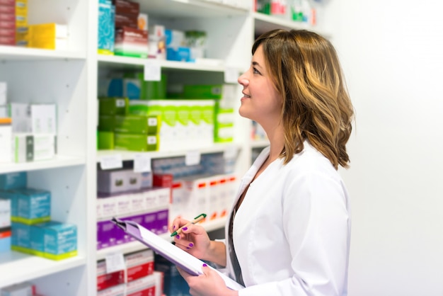 Vrouwenklant met een omslag in de apotheek die de geneesmiddelen op de plank bekijkt