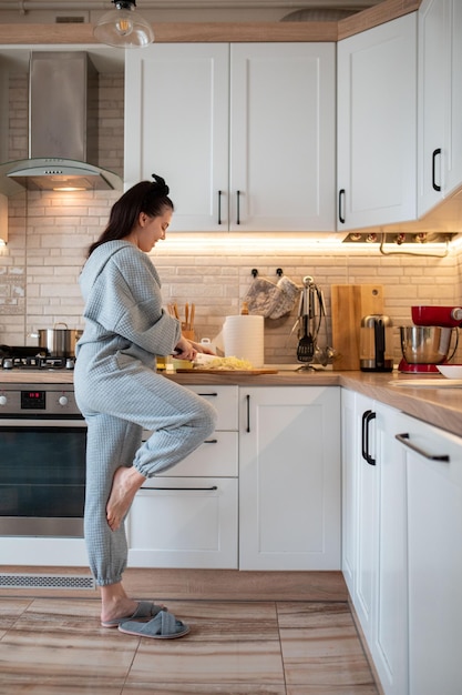 Vrouwenkooktoestel bij binnenlandse keuken die voedsel voorbereidt