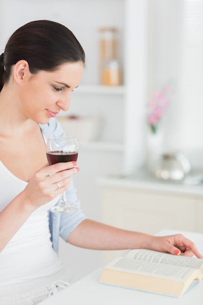 Vrouwenlezing terwijl het houden van een rode wijnglas