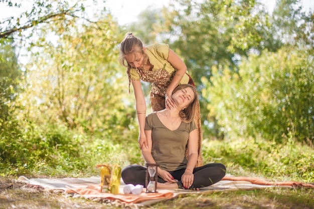 Vrouwenmasseuse past haar massagevaardigheden toe op haar cliënt op het gras van het bos.