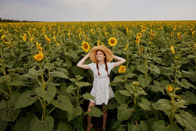 Vrouwenportret in een strohoed in een witte jurk een veld met zonnebloemen, landbouw zomertijd