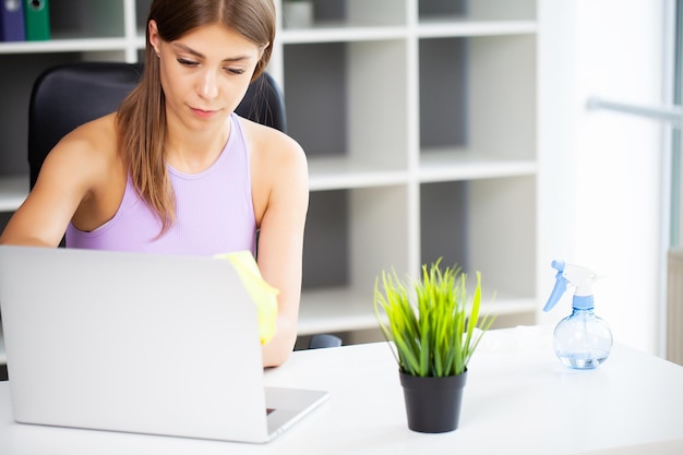 Vrouwenreiniger ruimt het computerbureau op kantoor op