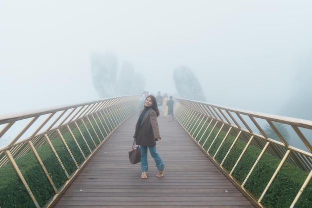 Vrouwenreiziger die de Gouden brug bezoekt op de top van het Ba Na Hills-oriëntatiepunt en het populaire reisconcept voor Vietnam en Zuidoost-Azië