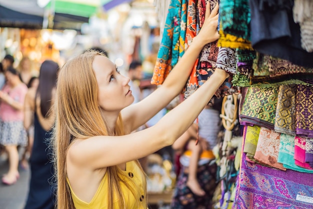 Vrouwenreiziger kiest souvenirs op de markt in Ubud in Bali, Indonesië