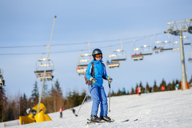 Vrouwenskiër die bergaf bij skitoevlucht skiën tegen skilift