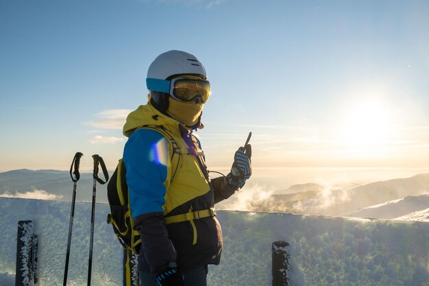 Vrouwenskiër die foto van zonsondergang boven de bergen op de telefoon neemt