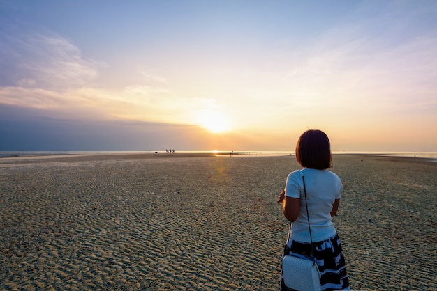 Vrouwentoerist die op het strand staan en kijken naar het prachtige natuurlijke landschap, kleurrijk van de lucht en de zee tijdens een zonsondergang bij Nathon Sunset Viewpoint op het eiland Ko Samui, Surat Thani, Thailand