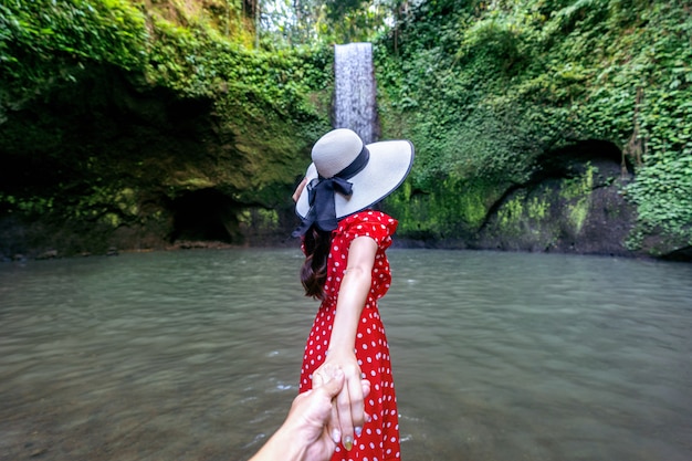 Vrouwentoeristen die man hand houden en hem naar Tibumana-waterval in Bali, Indonesië leiden.