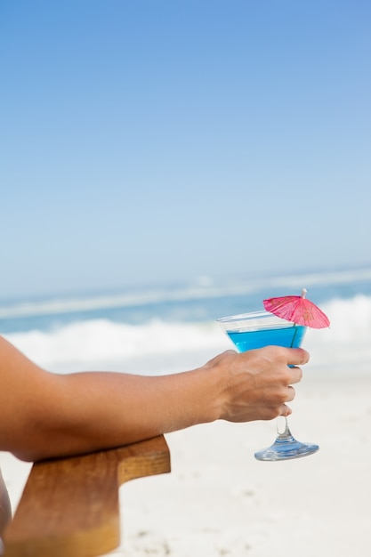 Vrouwenzitting als ligstoel met een cocktail bij het strand