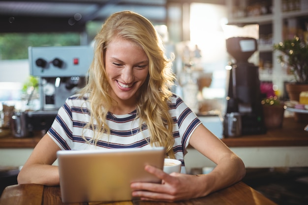 Vrouwenzitting in een koffie die digitale tablet gebruiken