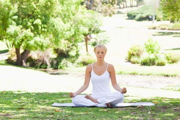 Vrouwenzitting in een yogapositie op het gazon