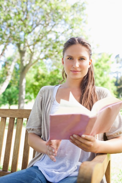 Vrouwenzitting op een parkbank met haar boek