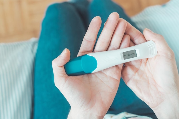 Vrouwenzitting op het bed die zwangerschapstest controleren Resultaat positief Zwanger