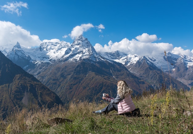 Vrouwreiziger drinkt koffie met uitzicht op het berglandschap