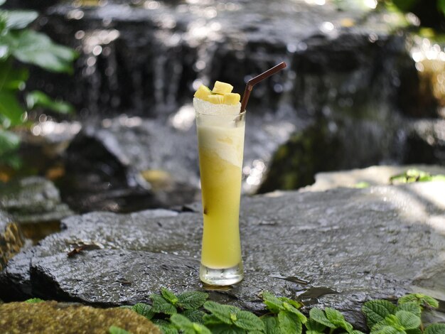 Foto vruchtensap fruit smoothie vruchtensap vruchtensap in glas geplaatst op een rots bij de waterval