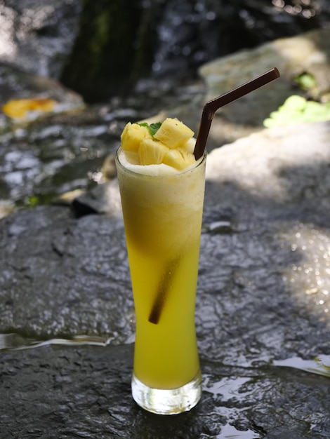 Vruchtensap fruit smoothie vruchtensap vruchtensap in glas Geplaatst op een rots bij de waterval