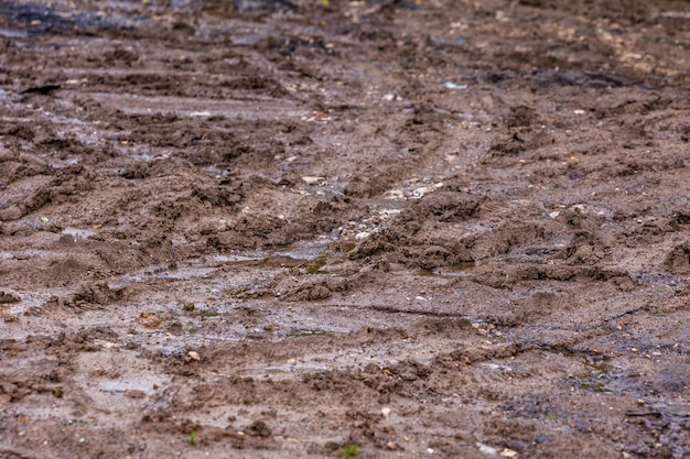 Vuile kleimodderweg met bandensporen close-up met selectieve focus en vervaging