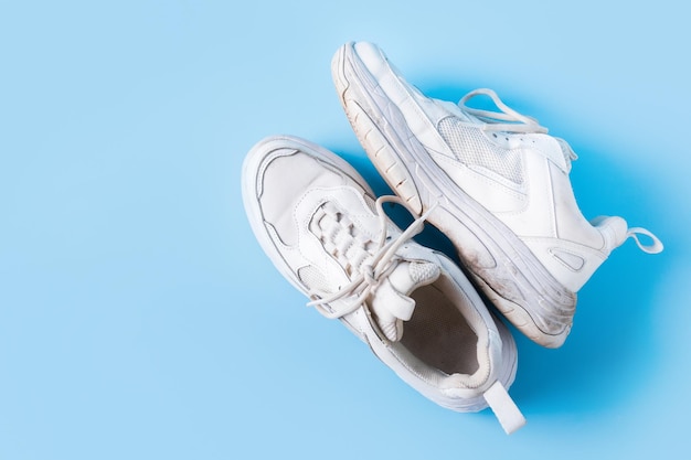 Vuile oude witte sneakers op blauwe achtergrond