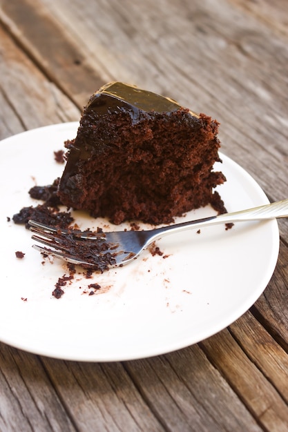 Vuile vork met gegeten huis gemaakt Chocolade cake op witte plaat.