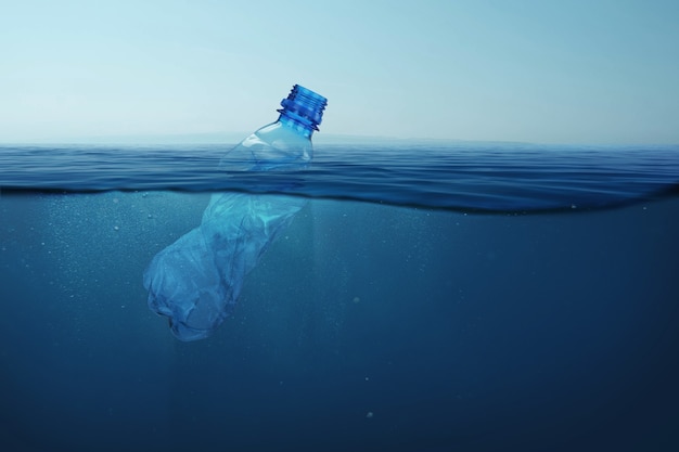 Vuilnis plastic fles drijft in blauw zeewater met onderwater. Vervuiling van het milieu en de oceanen.